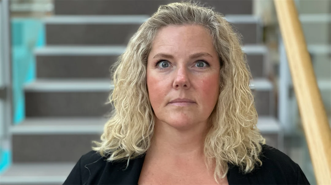 En kvinna med blont hår framför en trappa