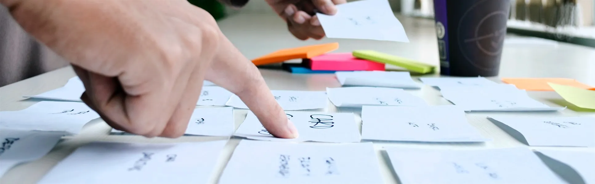 Två händer som ordnar post it lappar på ett bord