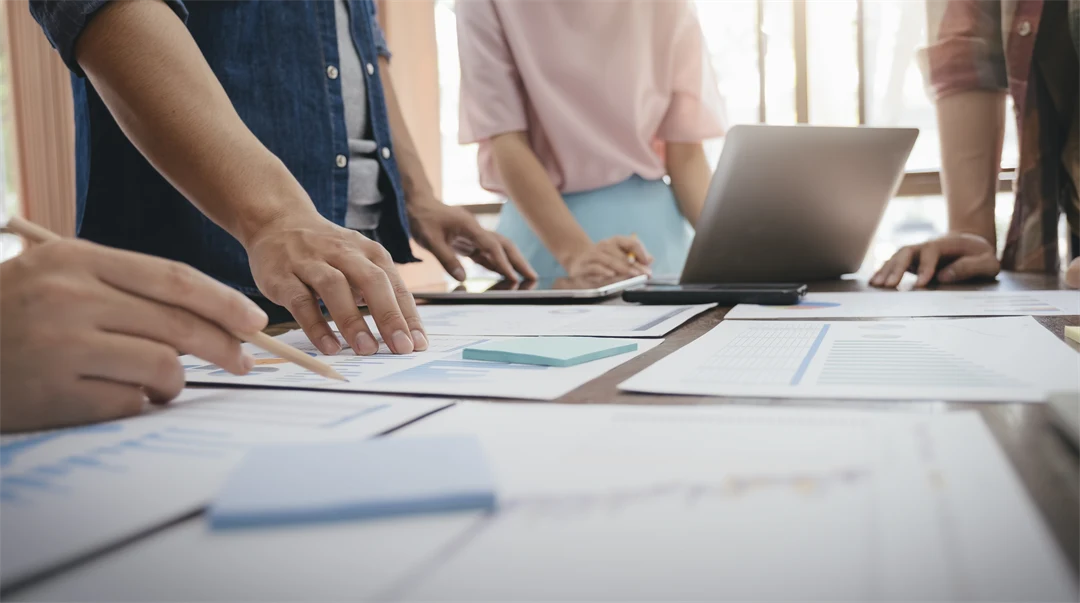 Bord med papper och människor som håller fram händerna