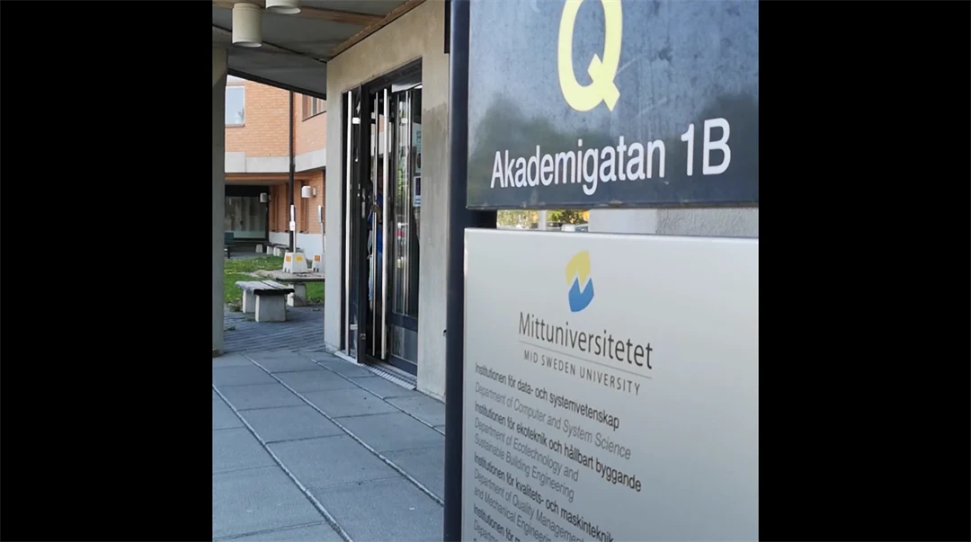 Kvinna i grå hoodie intervjuas framför tegelbyggnad