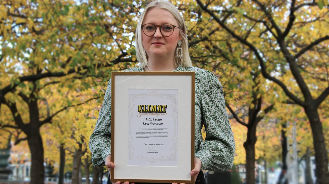 En tjej med som står utomhus och håller i ett inramat pris