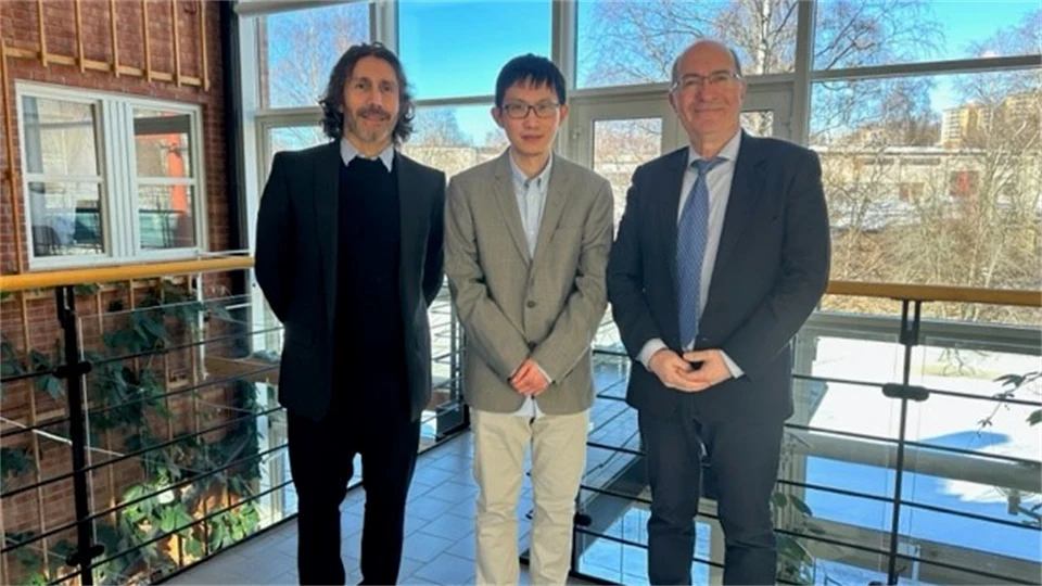 Tre finklädda personer står framför ett stort fönster