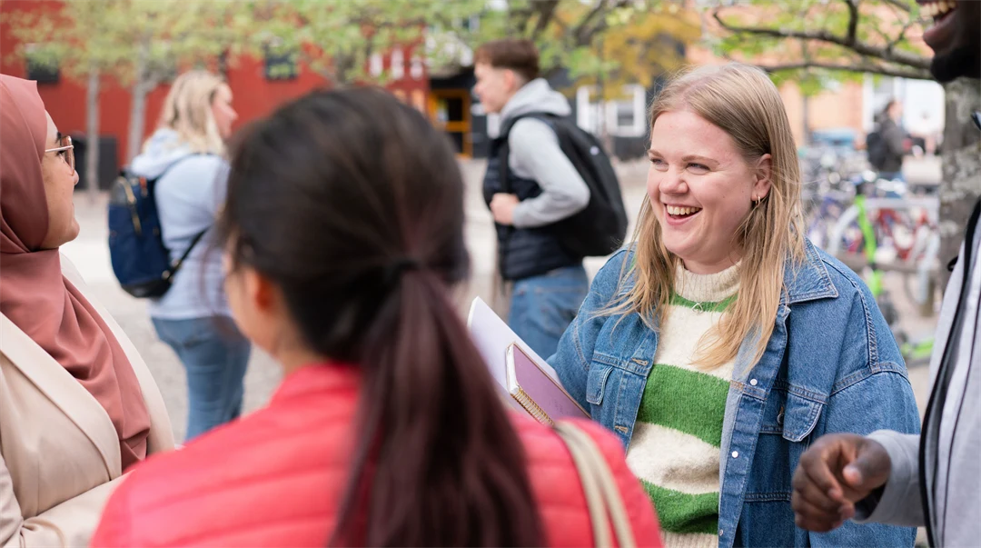 A group of students standing and talking to each other outside the campus.